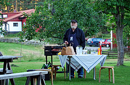 Krister står vid grillen och tillagar korv.